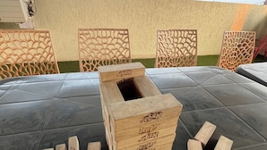 A table with a wooden block game in the center, surrounded by chairs with intricate back designs. - Aarna Villa nr Valvan Dam (Lonavala)