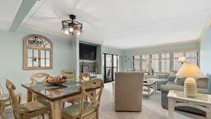 Amplia sala de estar con mesa de comedor, sillas, sofá y televisor.