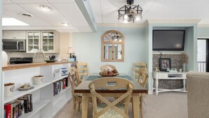 Una cocina moderna con armarios blancos, un microondas integrado y una zona de comedor con mesa y sillas de madera.