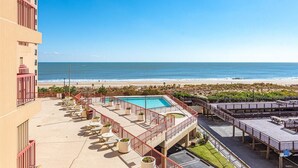 Zona de piscina en la azotea con vista a la playa, mobiliario exterior y cielo despejado.