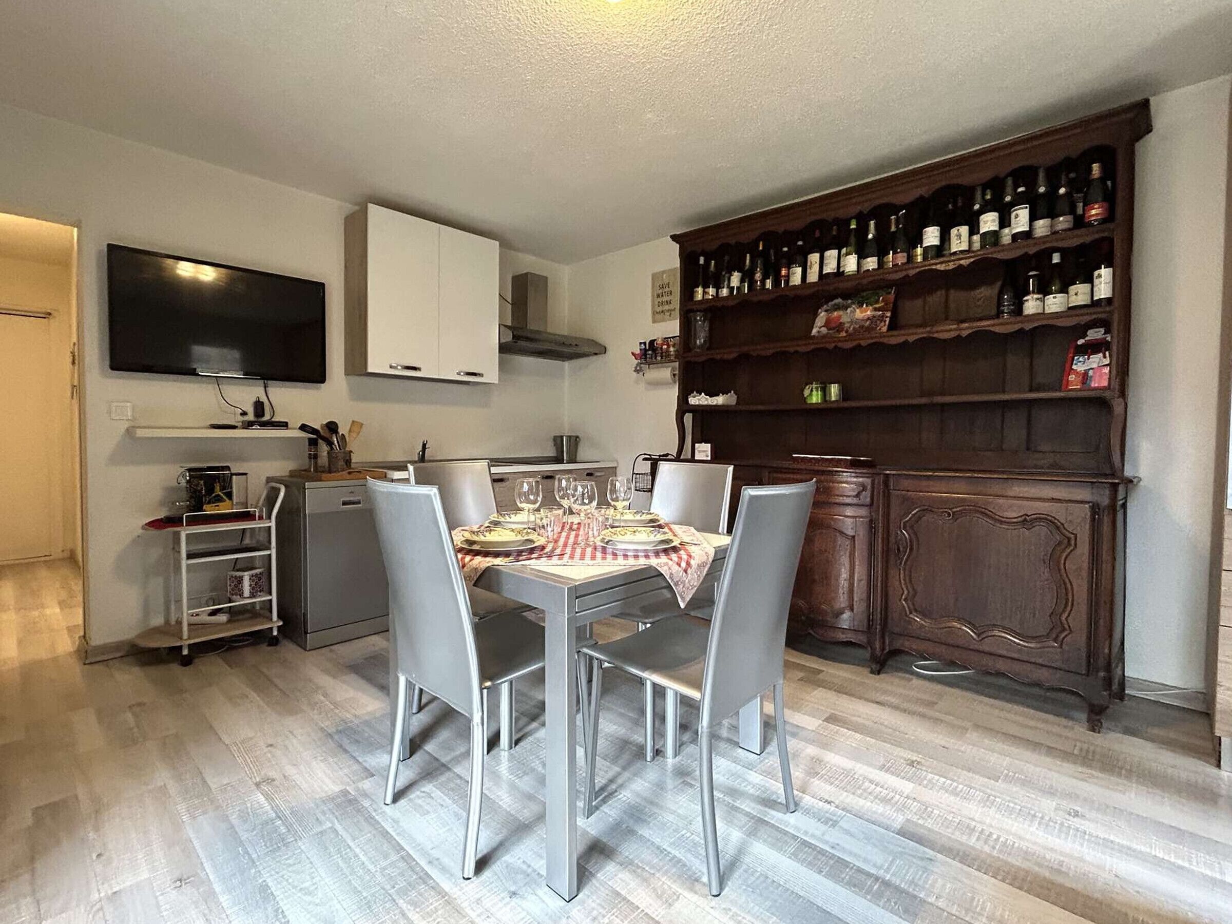 A modern kitchen with a dining table set for four, a built-in oven, and a wine rack.