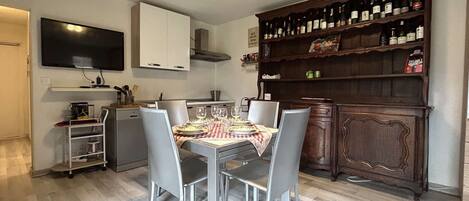A modern kitchen with a dining table set for four, a built-in oven, and a wine rack.