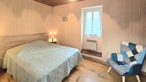 Ein Zimmer mit einem Bett, einem Sessel, einem Fenster und einer Deckenleuchte.