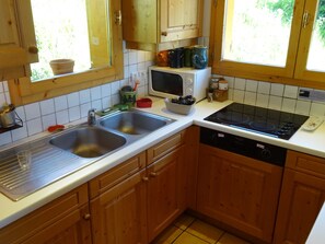 A kitchen with wooden cabinets, a double sink, a microwave, an induction cooktop, and a dishwasher. - Charming 5-Bedroom Chalet, 10 ppl, Vallandry (Peisey-Vallandry)