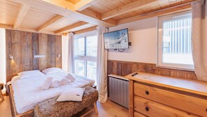 A wooden cabin room with a bed, a TV, and a wooden dresser. - Cozy apt for 6 in Val Thorens, near slopes (Val Thorens)
