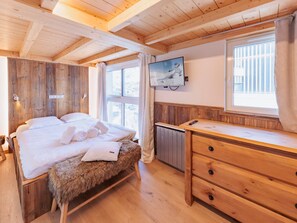 Ein Zimmer in einer Holzhütte mit einem Bett, einem Fernseher und einer Holzkommode.