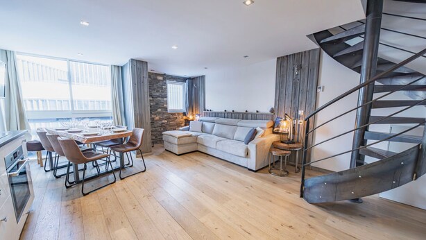 A modern living room with a dining area, a sofa, and a spiral staircase. - Cozy apt for 6 in Val Thorens, near slopes (Val Thorens)