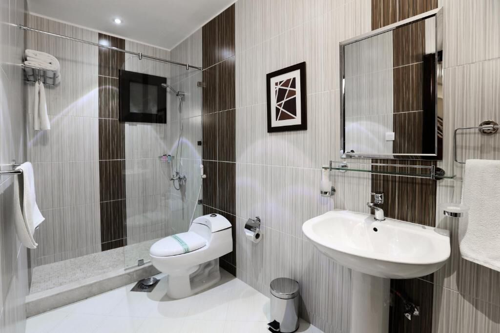 Egy modern fürőszoba, amelyben WC, mosdókagyló és zuhanyzó található.