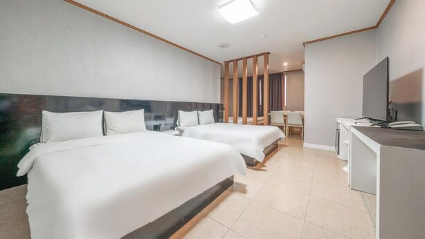 A hotel room with two beds, a desk, a TV, and a window. - Hotel Lisa (Donghae)