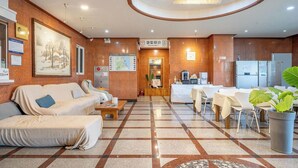 A hotel lobby with a reception desk, seating area, and a large painting on the wall. - Hotel Lisa (Donghae)