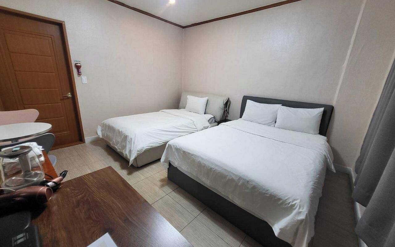 A hotel room with two beds, a wooden desk, and a small table.