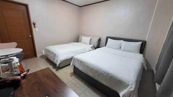 A hotel room with two beds, a wooden desk, and a small table.