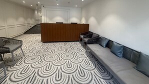 Uma área de recepção moderna com piso estampado, balcão de atendimento, espaço de estar e escada.