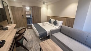 Quarto de hotel moderno com cama, sofá, escrivaninha e cadeira.