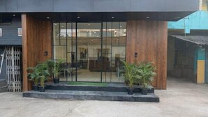 Um edifício moderno com entrada de vidro, detalhes em madeira e plantas em vasos.