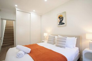 Ein Hotelzimmer mit Bett, einem Gemälde, einem Nachttisch und einer Tür.