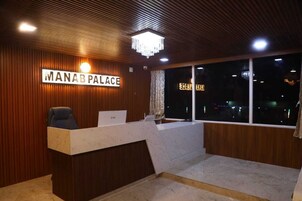 Una recepción con un cartel que dice "MANAB PALACE" y vistas de la ciudad por la noche.