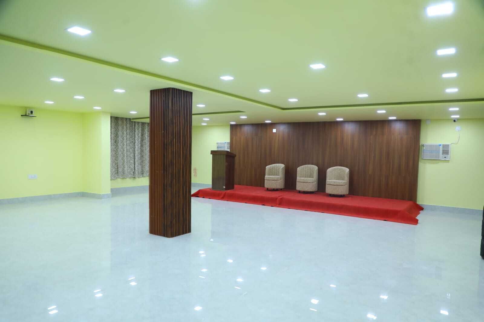A conference room with a podium, three chairs, a red carpet, and a tall column.
