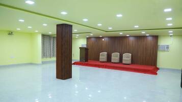 A conference room with a podium, three chairs, a red carpet, and a tall column.