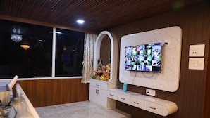 Een moderne keuken met een marmeren aanrechtblad, houten kastjes, een ingebouwde televisie en een raam met gordijnen.