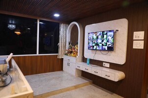 Una cocina moderna con encimera de mármol, armarios de madera, televisión integrada y una ventana con cortinas.