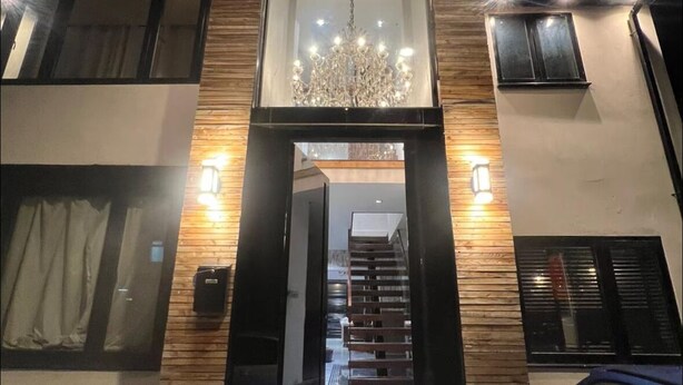 A modern building entrance with a glass door, wooden paneling, and a chandelier. - Elegant family home, 2x jacuzzi corner baths, Contract Workers and NHS Welcome. (Luton)