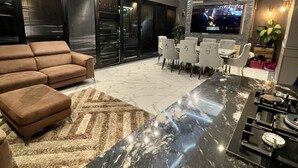 A modern living room with a high ceiling, a skylight, a large flat-screen TV, and a dining area. - Elegant family home, 2x jacuzzi corner baths, Contract Workers and NHS Welcome. (Luton)