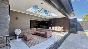 A modern living room with a sectional sofa, a fan, and a glass ceiling.