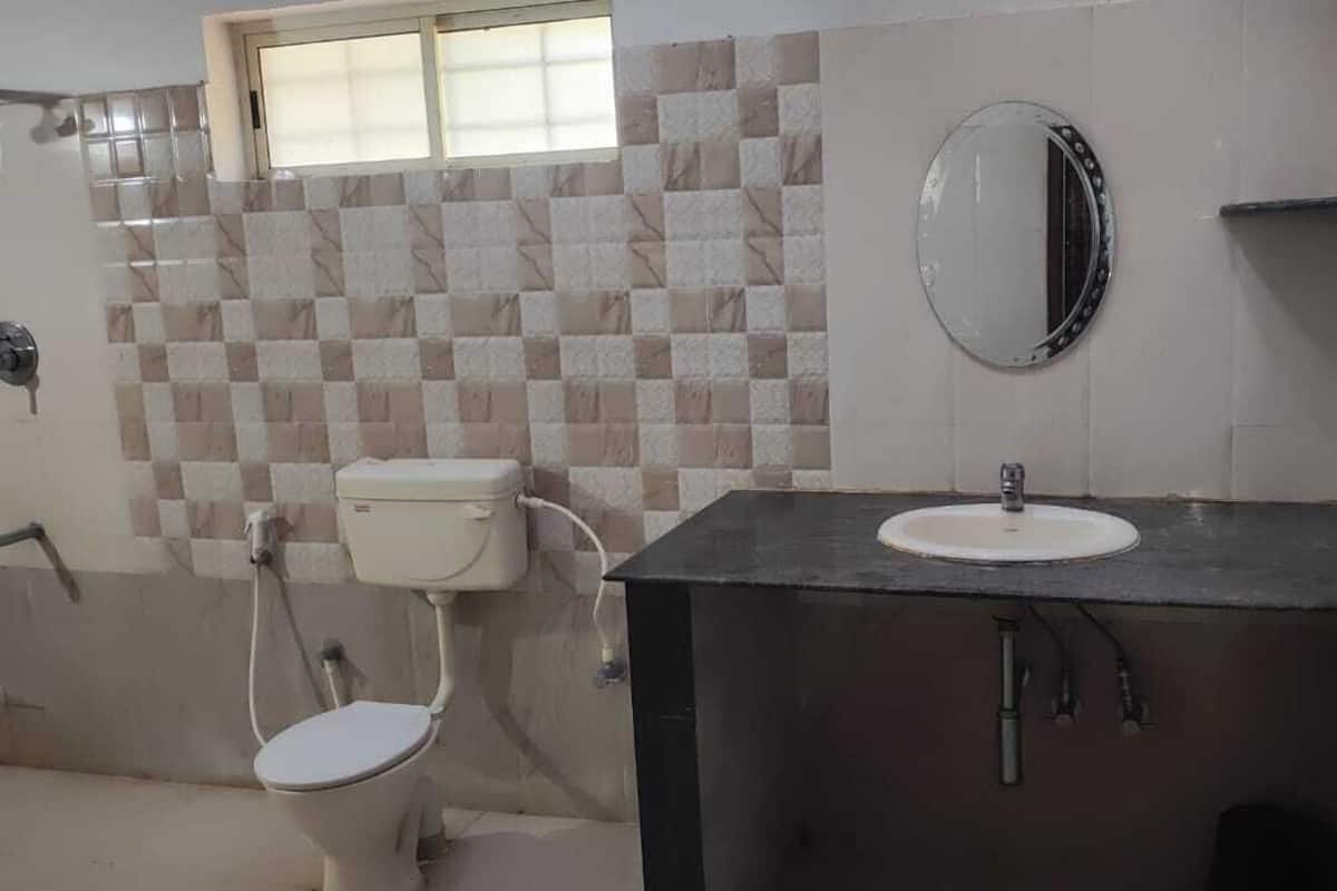 A bathroom with a toilet, sink, and mirror.