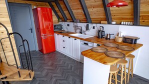 A modern kitchen with a herringbone floor pattern, a red refrigerator, and a wooden island with stools.