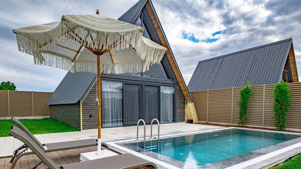 A swimming pool with lounge chairs and a canopy, surrounded by a wooden deck and a grassy lawn.