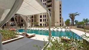 A swimming pool with lounge chairs, a lifebuoy, and a covered area with a canopy. - Stayshort - Bright 1 Bedroom in Madinat Jumeirah Lving That Sleeps 2 (Dubai)