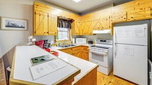 Une cuisine avec des meubles de rangement en bois, un réfrigérateur blanc, un four à micro-ondes, une cuisinière et un évier.