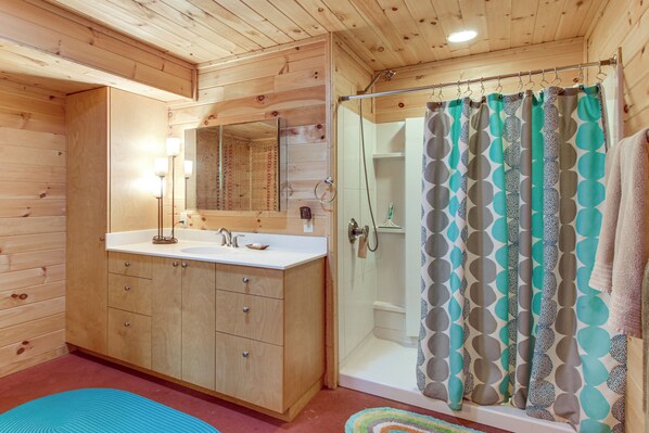 A wooden cabin bathroom with a sink, mirror, and shower.