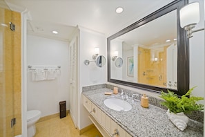 Un baño con lavamanos blanco, un espejo grande y una planta en maceta.