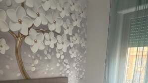 Un dormitorio moderno con una cama grande, ropa de cama blanca y un muro decorativo con flores blancas.