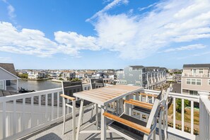 Un balcon avec une table et des chaises donnant sur un quartier résidentiel et un plan d’eau.