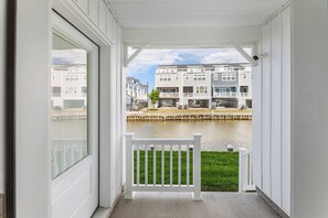 Une véranda avec une balustrade blanche, une vue sur un plan d’eau et, au loin, des immeubles à plusieurs étages.