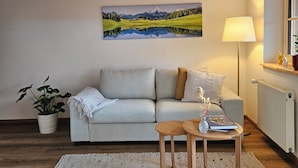 Un salon chaleureux avec un escalier en bois, un canapé, une petite table et une plante en pot.