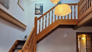 Un escalier en bois avec une rampe, une table à manger avec des chaises et un luminaire suspendu.