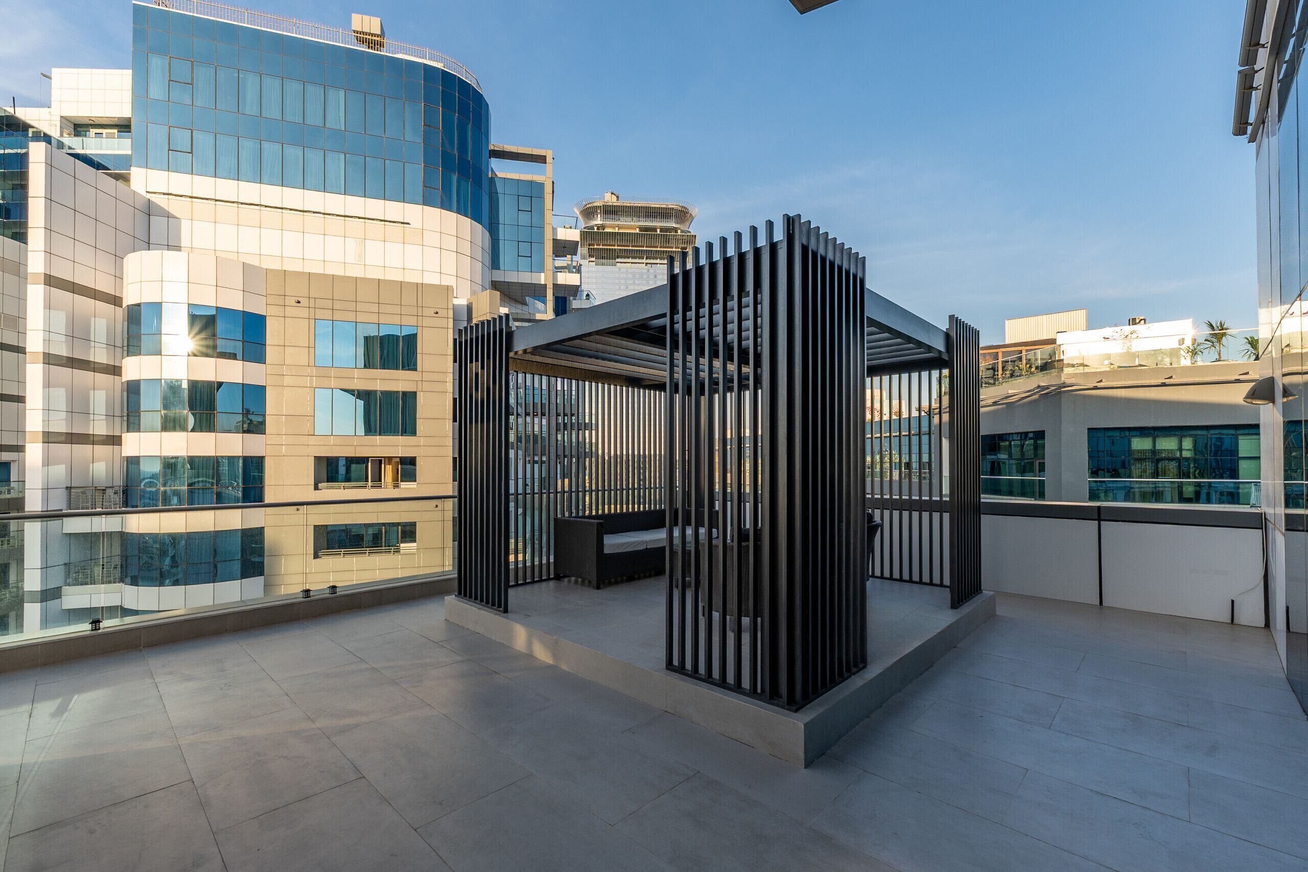 Terrassa al terrat amb zona d'estar moderna, baranes de vidre i vista als edificis circumdants.