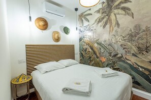 Un dormitorio con cama, aire acondicionado de pared, un adorno en la pared y una mesita de noche.