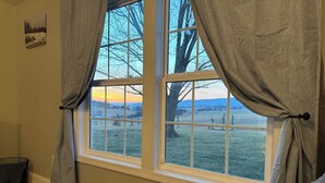 A room with a large window, a bed, and a small table. - Circle F Ranch Bunkhouse- Charming farm stay in Shenandoah county- whole house (Edinburg)