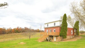Une maison à deux étages avec une terrasse en bois et des fondations en pierre.