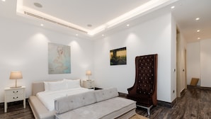 Een moderne slaapkamer met een bed, nachtkastjes, een bankje en kunstwerken aan de muur.