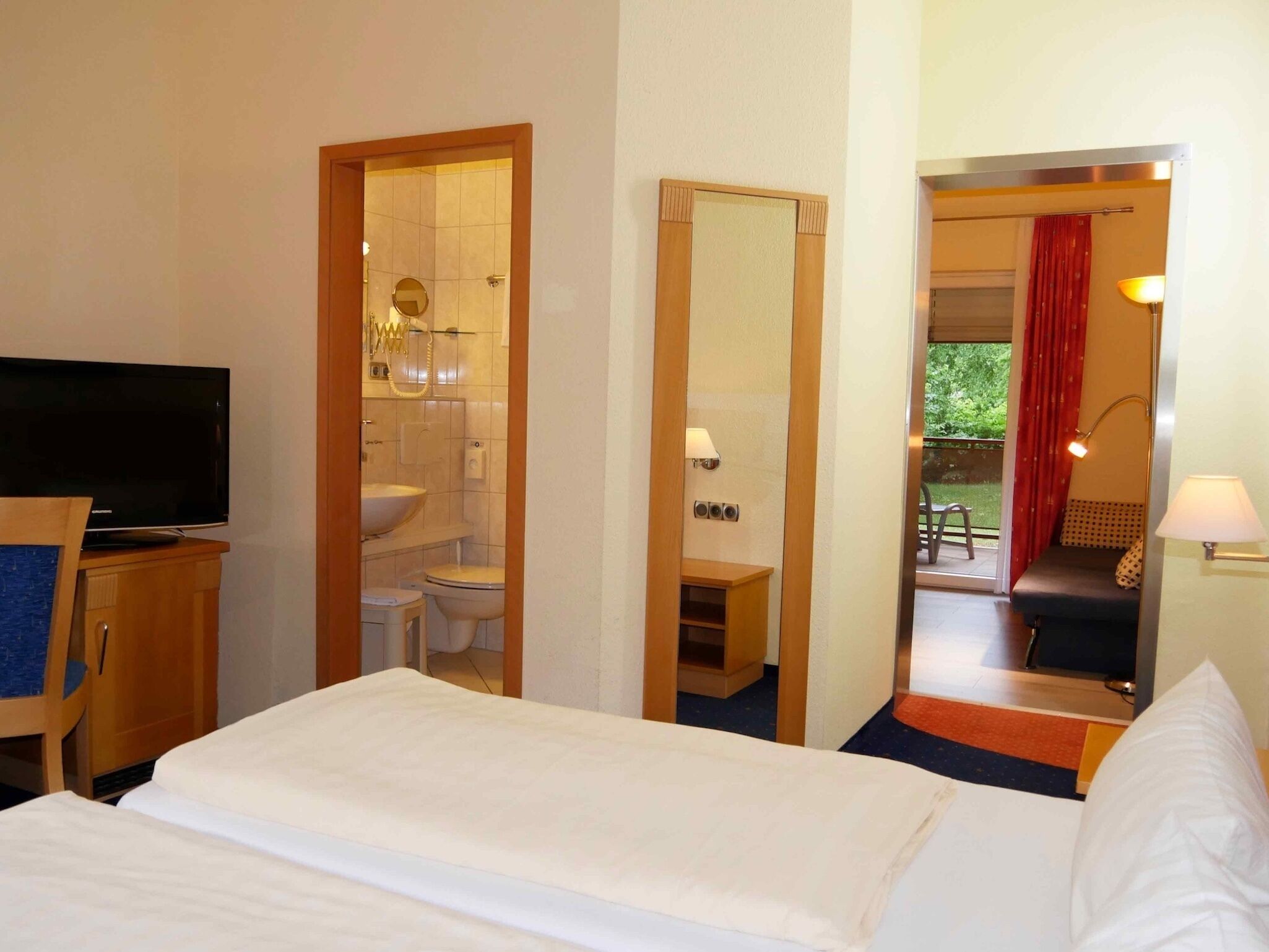 Une chambre d’hôtel équipée d’un lit, d’une télévision, d’une salle de bain et offrant une vue sur l’extérieur.