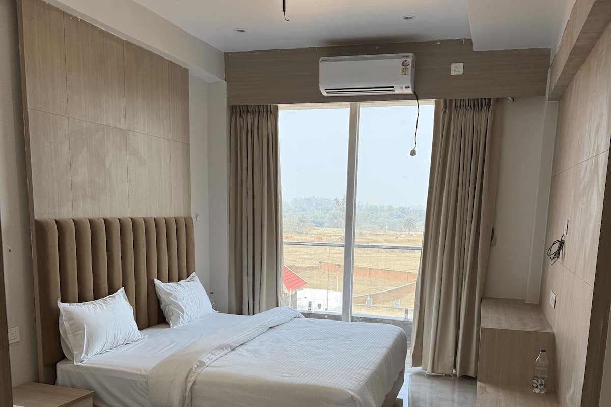 Une chambre moderne avec un grand lit, une table de chevet, un tapis rouge et une vue sur l’extérieur.