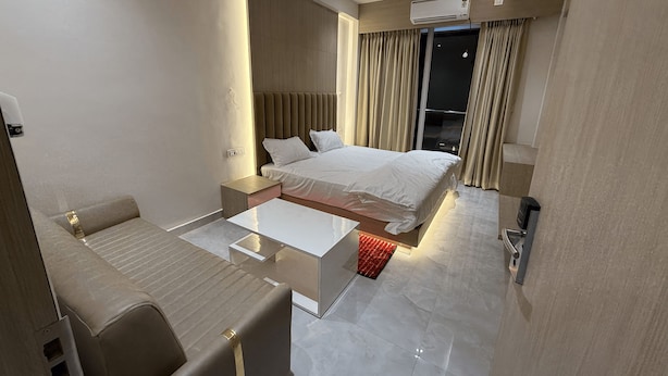 Habitación de hotel moderna con cama, escritorio, silla, una mesita y ventana con cortinas.