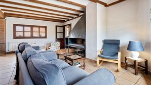 A living room with a sofa, a chair, a table, and a fireplace. - Townhouse in Rojals (Montblanc)