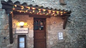 A stone building with a sign reading "La Socarrimada" and another sign indicating a cafe bar and menagerie. - Townhouse in Rojals (Montblanc)